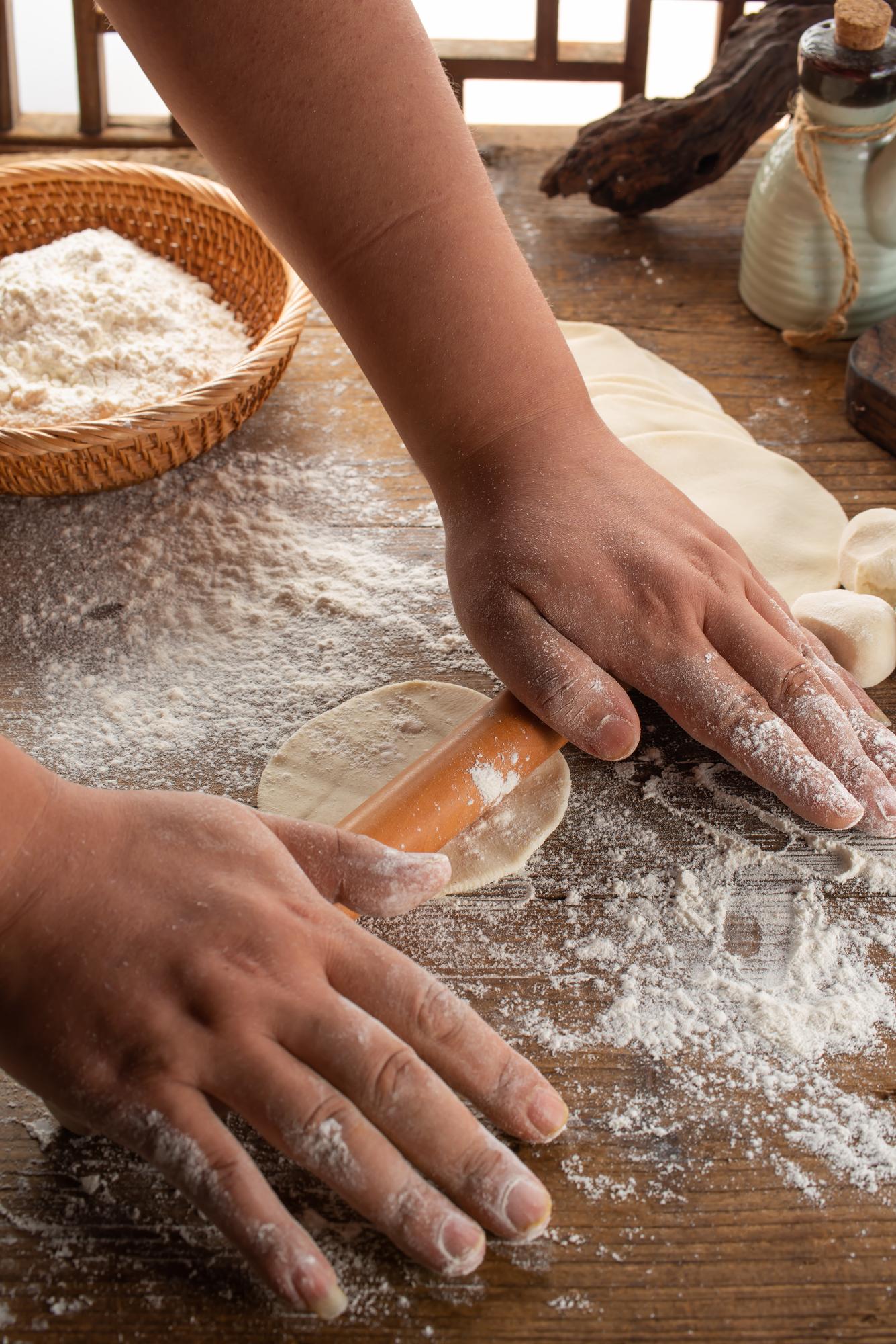 Hands kneading dough on floured surface