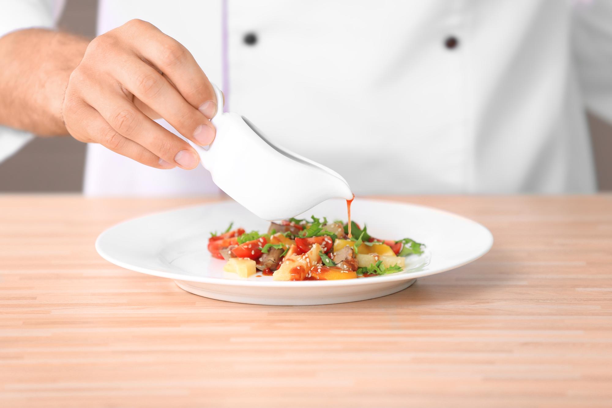 Chef preparing plated dish on wooden table